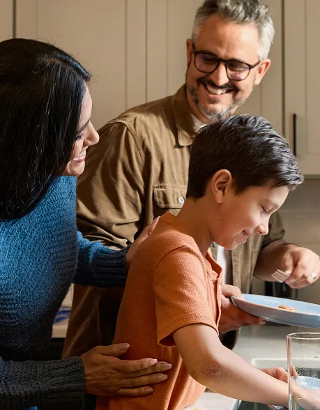 Family in kitchen cleaning dishes together
